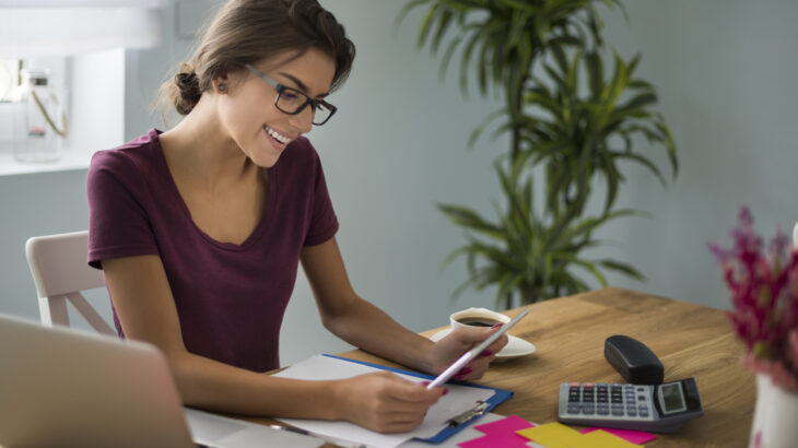 Una mujer analizando documentos y gastos en casa para evaluar qué tener en cuenta antes de pedir un préstamo personal.